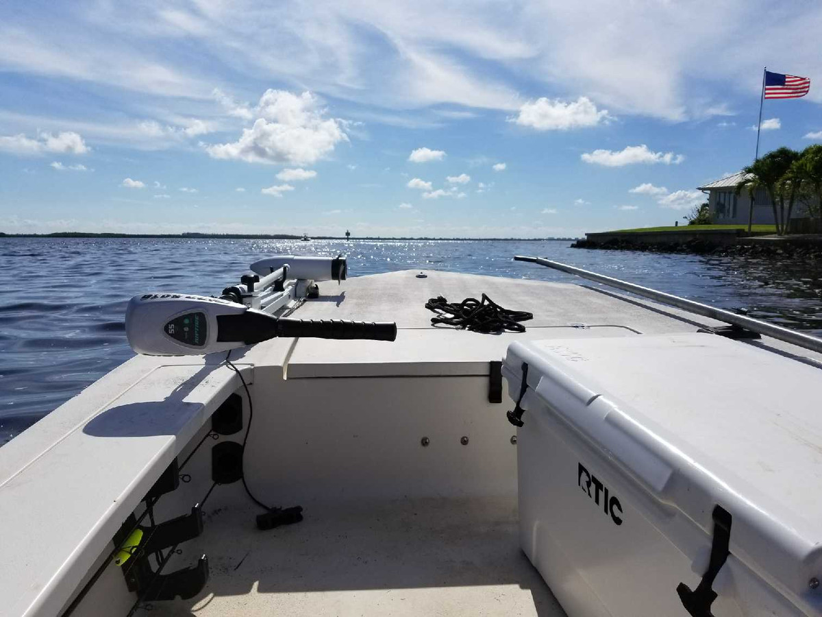 Bow of the skiff underway on a Southwest Florida bay with the US flag ashore